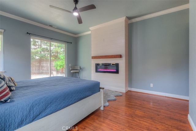 bedroom with access to exterior, crown molding, a large fireplace, ceiling fan, and hardwood / wood-style flooring