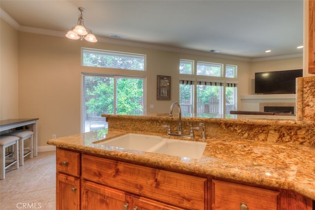 kitchen featuring light stone counters, a fireplace, sink, and a healthy amount of sunlight