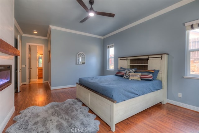 bedroom featuring crown molding, connected bathroom, hardwood / wood-style floors, and ceiling fan