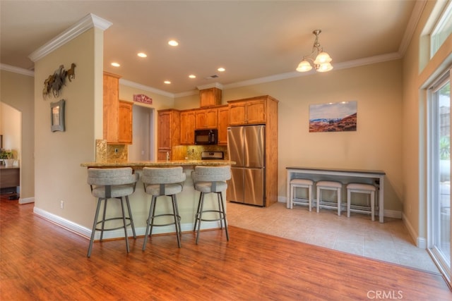 kitchen with decorative backsplash, light wood-type flooring, kitchen peninsula, and stainless steel fridge