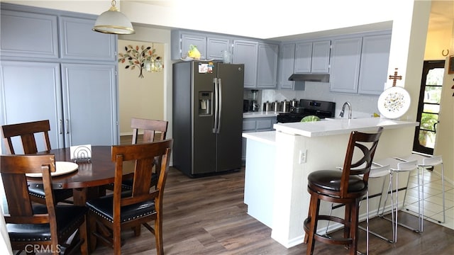 kitchen with a breakfast bar, pendant lighting, stainless steel fridge with ice dispenser, kitchen peninsula, and range with electric cooktop