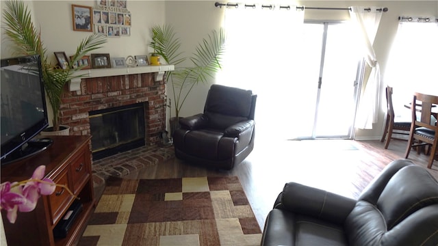 living room with a wall mounted air conditioner, a brick fireplace, and a wealth of natural light