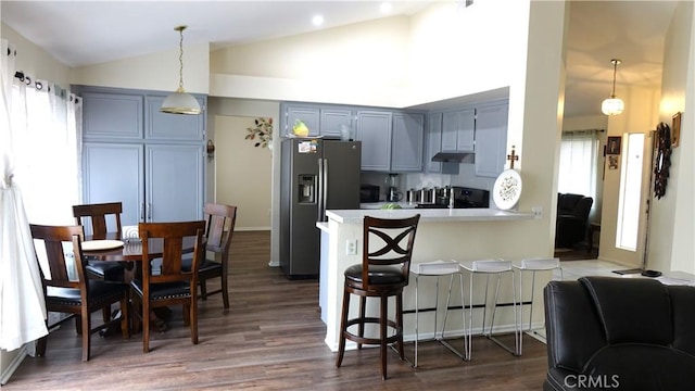 kitchen with stainless steel fridge, hanging light fixtures, a kitchen bar, dark hardwood / wood-style flooring, and kitchen peninsula