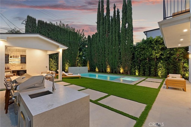 exterior space featuring a lawn, outdoor lounge area, a balcony, and an outdoor kitchen