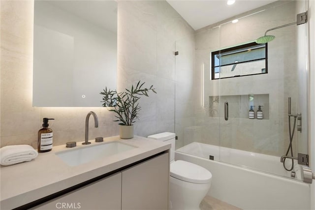 full bathroom with combined bath / shower with glass door, decorative backsplash, vanity, tile walls, and toilet