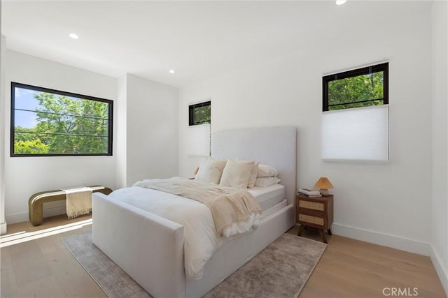 bedroom with hardwood / wood-style flooring and multiple windows