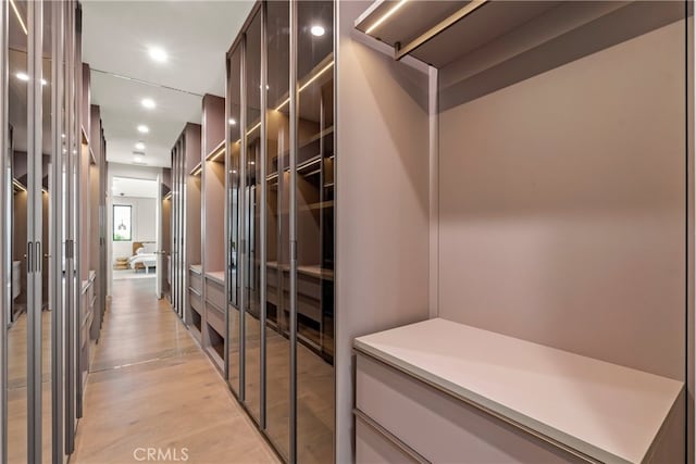 walk in closet with light hardwood / wood-style floors