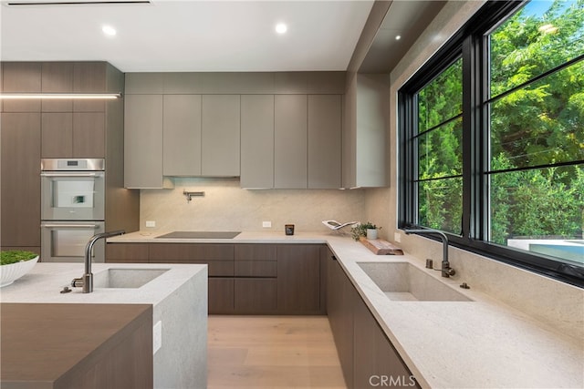 kitchen with light hardwood / wood-style floors, double oven, gray cabinetry, and sink