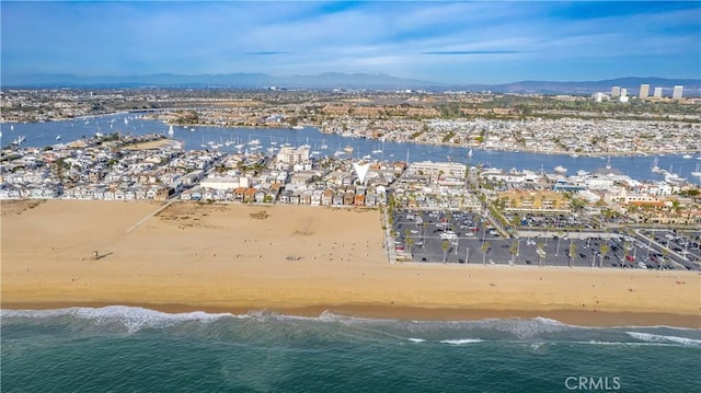 drone / aerial view with a beach view and a water and mountain view