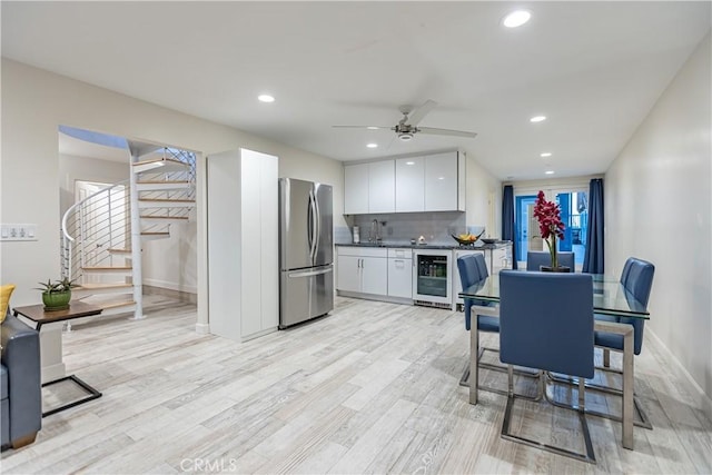 kitchen featuring light hardwood / wood-style flooring, stainless steel refrigerator, backsplash, white cabinets, and beverage cooler