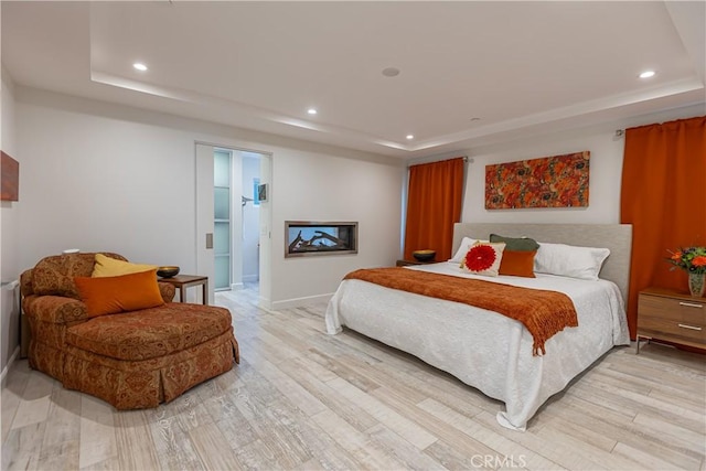 bedroom featuring a tray ceiling and light wood-type flooring