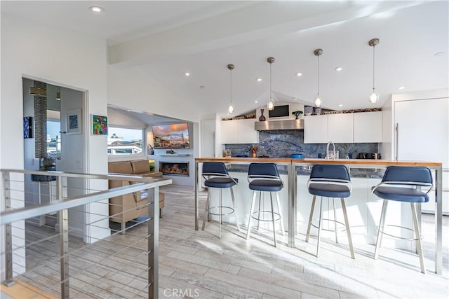 kitchen with hanging light fixtures, white cabinets, and lofted ceiling with beams