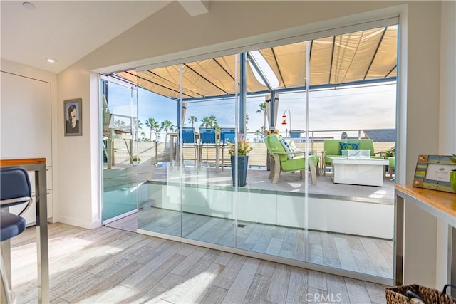 doorway to outside featuring lofted ceiling and light hardwood / wood-style floors