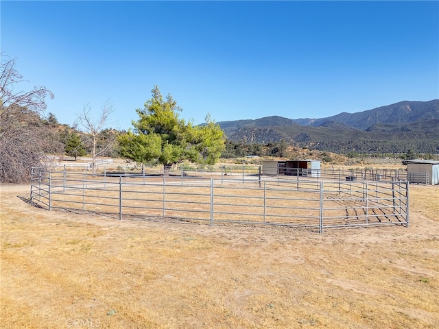 view of yard with an exterior structure, an outbuilding, a rural view, and a mountain view