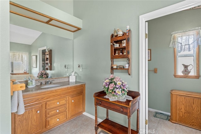 bathroom featuring baseboards, vaulted ceiling, tile patterned flooring, and vanity