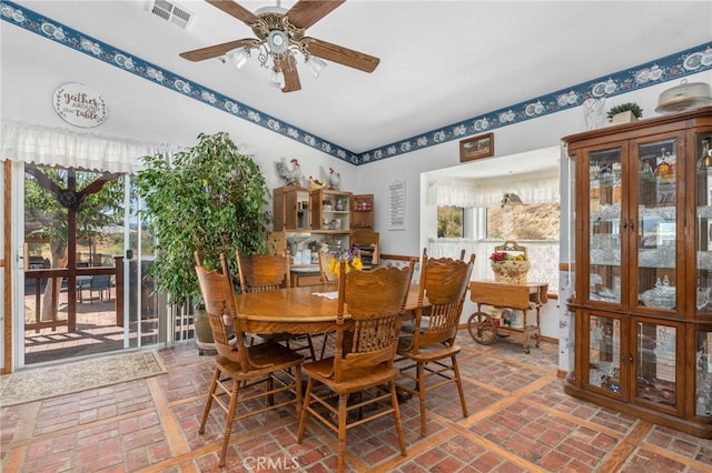 dining space with brick floor, visible vents, and plenty of natural light