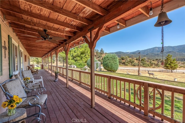 wooden deck with a mountain view, a yard, and ceiling fan