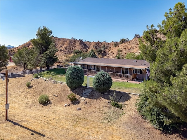 rear view of property featuring a lawn, a porch, fence, and a mountain view