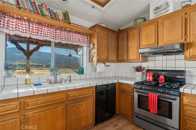 kitchen featuring sink, stainless steel gas range oven, tile countertops, a mountain view, and dishwasher