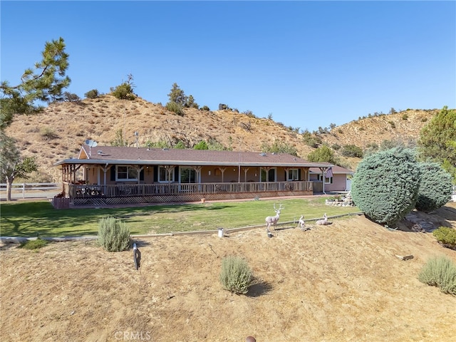 rear view of property featuring covered porch, a yard, and a mountain view