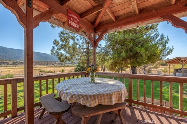 wooden terrace featuring a gazebo, a mountain view, a lawn, and a rural view