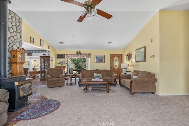 carpeted living room featuring a wood stove, a ceiling fan, high vaulted ceiling, and visible vents
