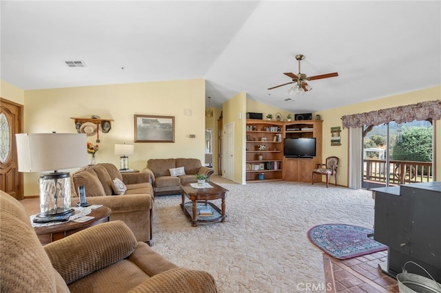 living room with vaulted ceiling, ceiling fan, carpet floors, a wood stove, and visible vents