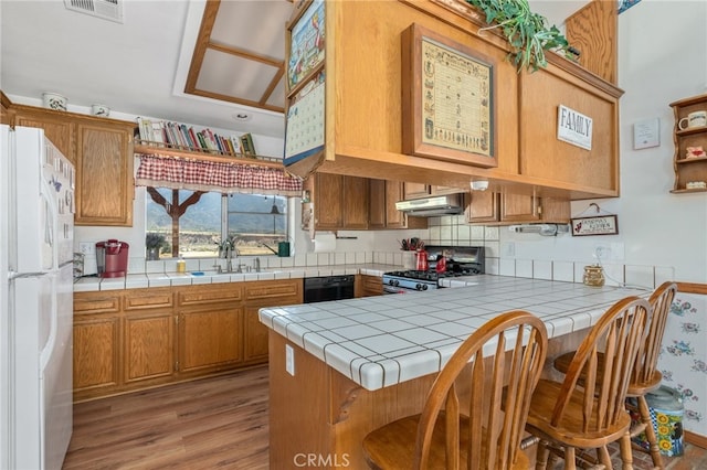 kitchen with white refrigerator, tile countertops, and kitchen peninsula