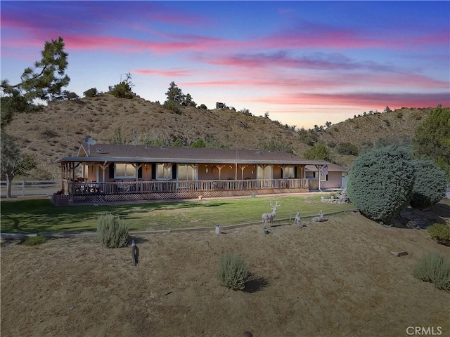 back of house at dusk featuring a yard, a porch, and a mountain view