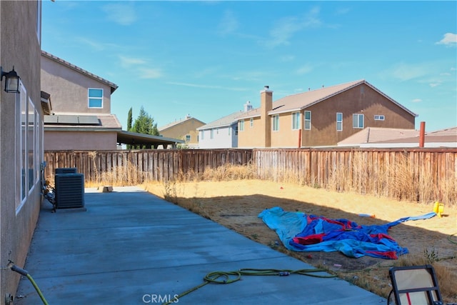 view of yard featuring a residential view, central AC unit, a fenced backyard, and a patio area