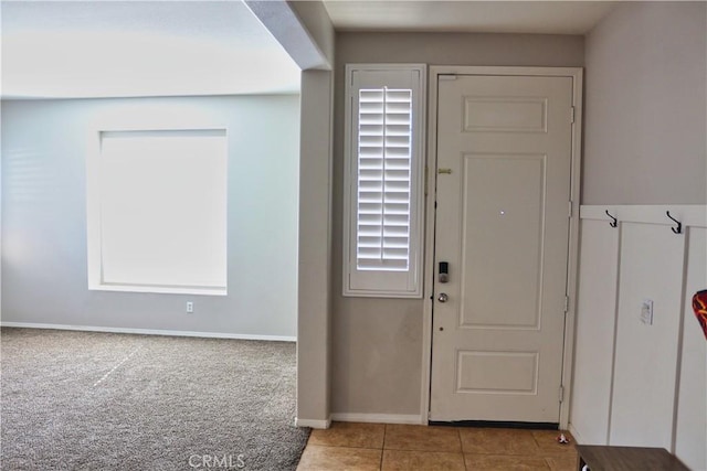 tiled entrance foyer featuring carpet and baseboards