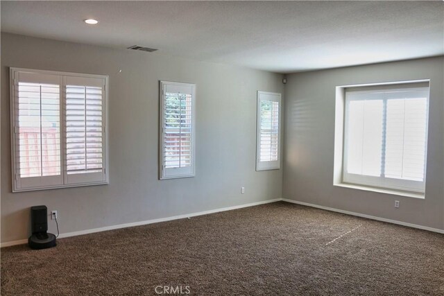 carpeted spare room with a textured ceiling and a healthy amount of sunlight