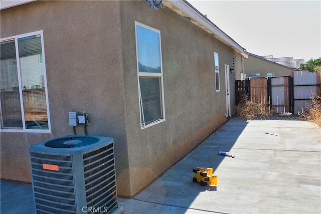 view of property exterior featuring fence, central AC, and stucco siding