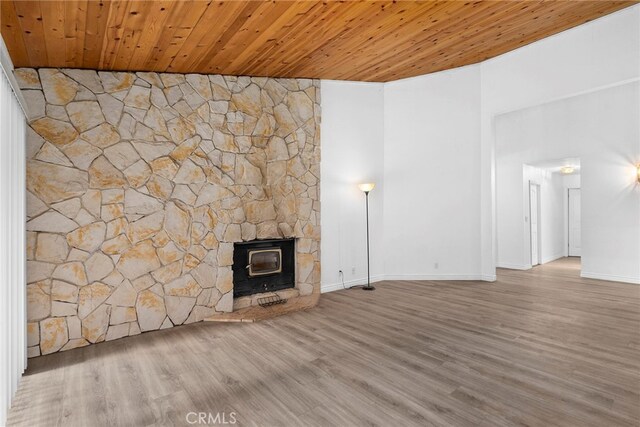 unfurnished living room featuring wooden ceiling, hardwood / wood-style floors, and a wood stove