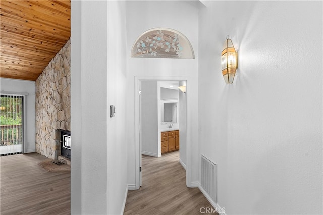 hall featuring light hardwood / wood-style flooring, a high ceiling, and wooden ceiling