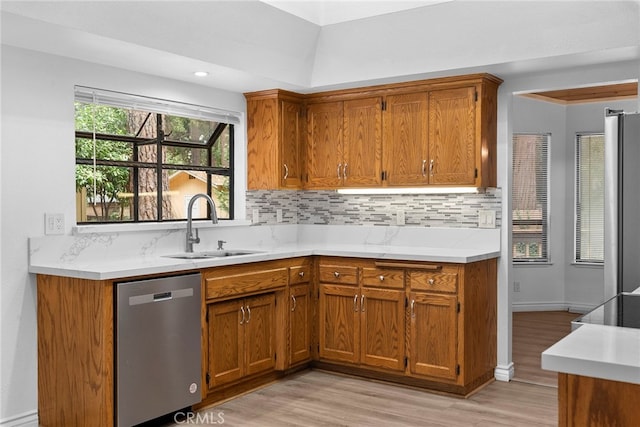 kitchen with stainless steel appliances, light hardwood / wood-style floors, backsplash, and sink