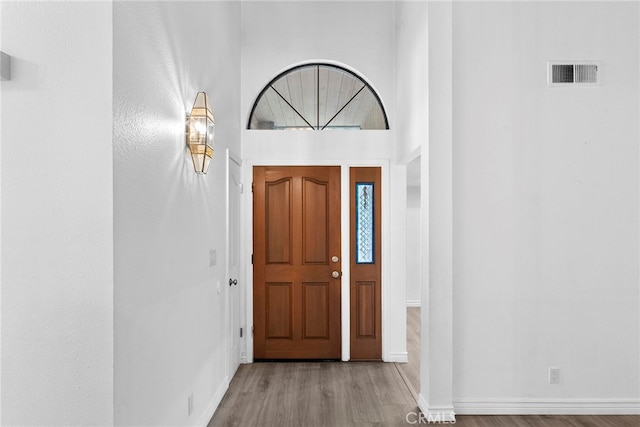 foyer entrance featuring a towering ceiling and light hardwood / wood-style flooring