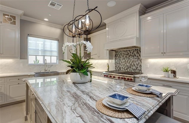 kitchen with tasteful backsplash, sink, an inviting chandelier, stainless steel stove, and white cabinetry