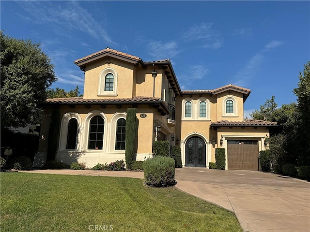 mediterranean / spanish-style home featuring a front lawn, a garage, and french doors