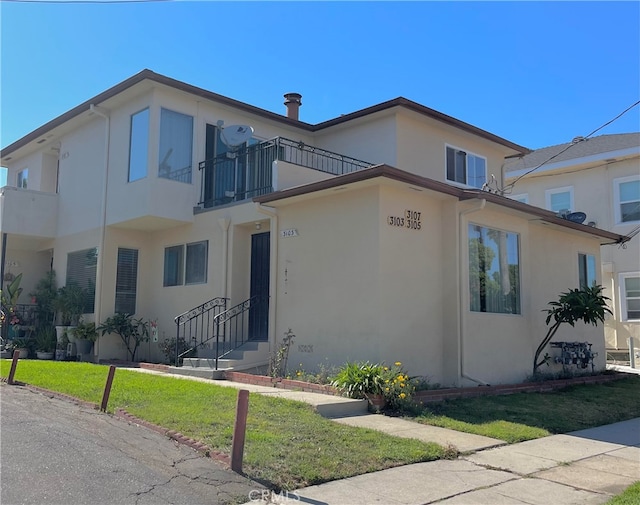 view of front of house featuring a balcony and a front lawn