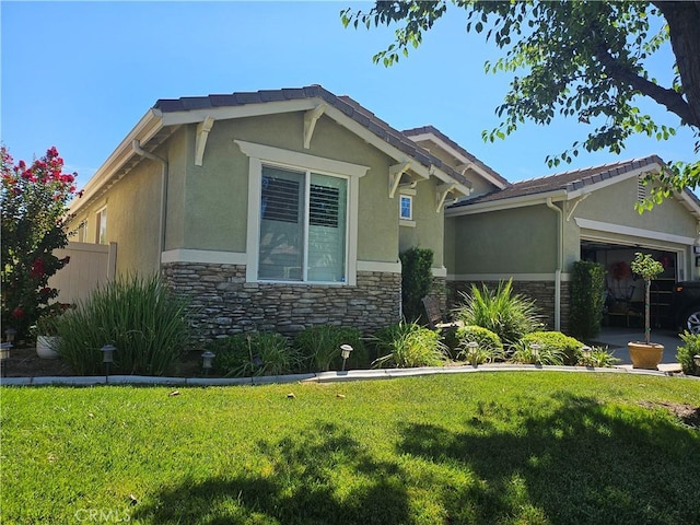 view of side of home featuring stone siding, a lawn, an attached garage, and stucco siding