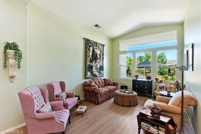 sitting room with lofted ceiling, wood finished floors, and visible vents