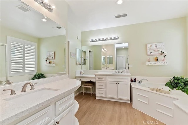 full bath with a garden tub, visible vents, a sink, and wood finished floors