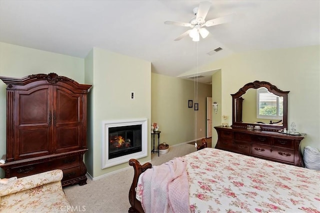 bedroom featuring light carpet, visible vents, a ceiling fan, a glass covered fireplace, and vaulted ceiling