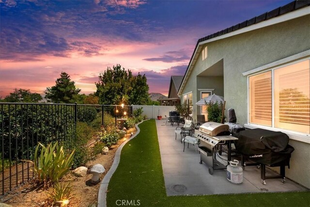 patio terrace at dusk featuring a grill