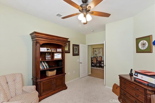 living area with a ceiling fan, light colored carpet, visible vents, and baseboards