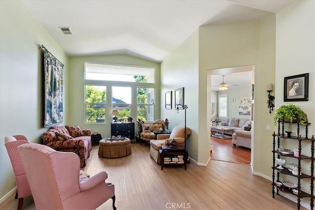 living area with light wood-type flooring, high vaulted ceiling, baseboards, and visible vents