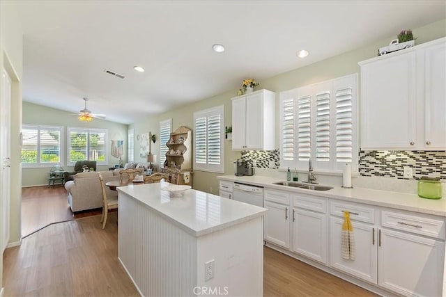 kitchen with visible vents, light wood-style flooring, a kitchen island, a sink, and white dishwasher