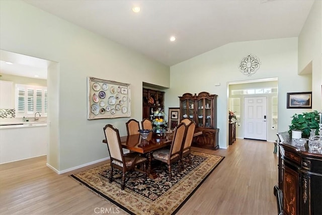 dining room with light wood-style flooring, baseboards, vaulted ceiling, and recessed lighting