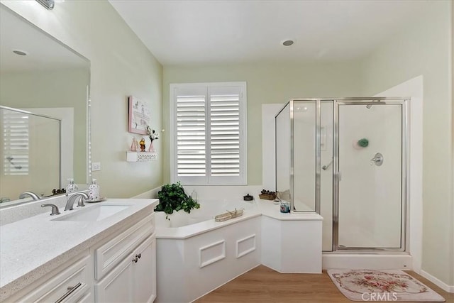 bathroom featuring a stall shower, a garden tub, wood finished floors, and vanity